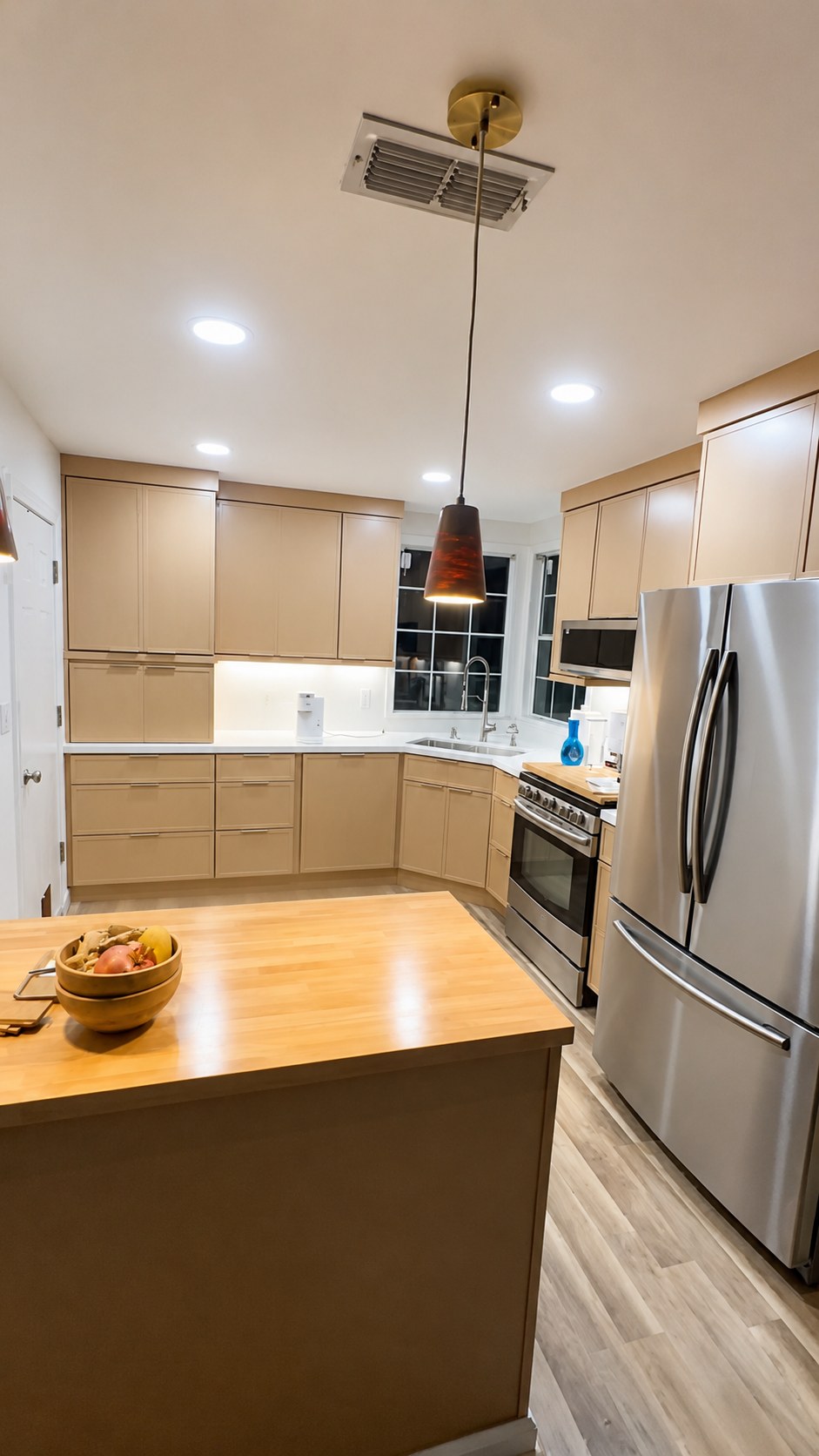 Kitchen remodel with beige cabinetry and butcher block island